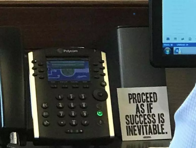 Photo of an employee desk at Freedom Mortgage with a sign reading Proceed as if success is inevitable