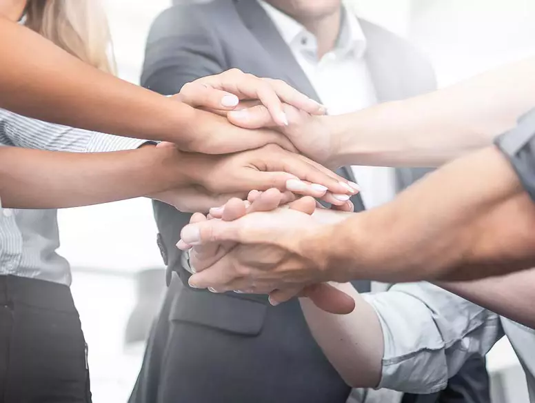 Image of multiple business people with hands held in center of circle