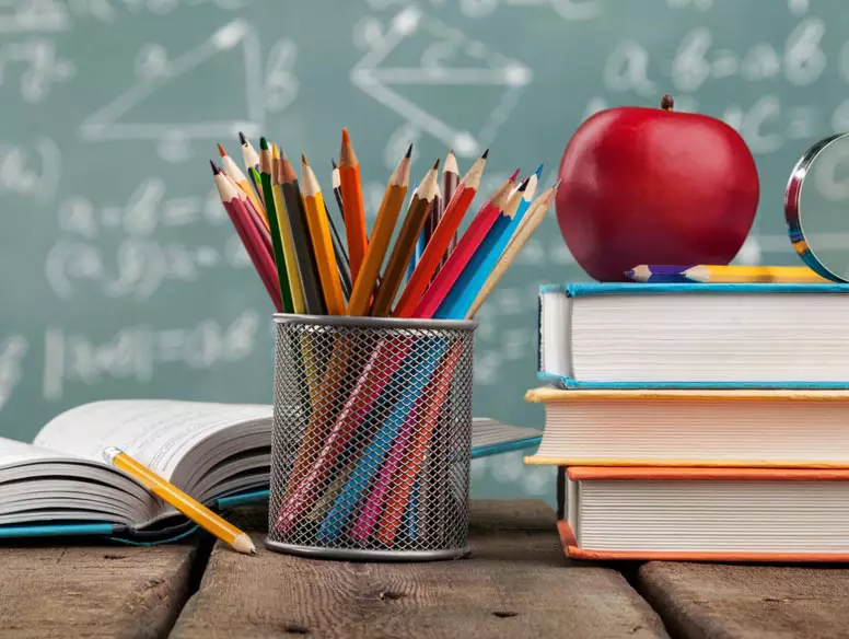 Image of a teachers desk with books, an apple, and colored pencils
