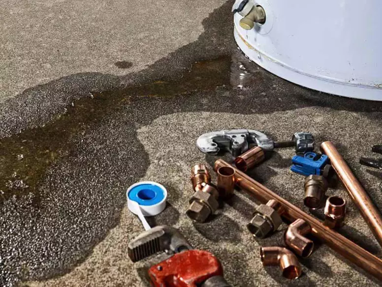 Close-up image of leaking water heater and repair tools