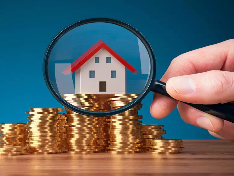 Magnifying glass examining a toy house on a stack of coins