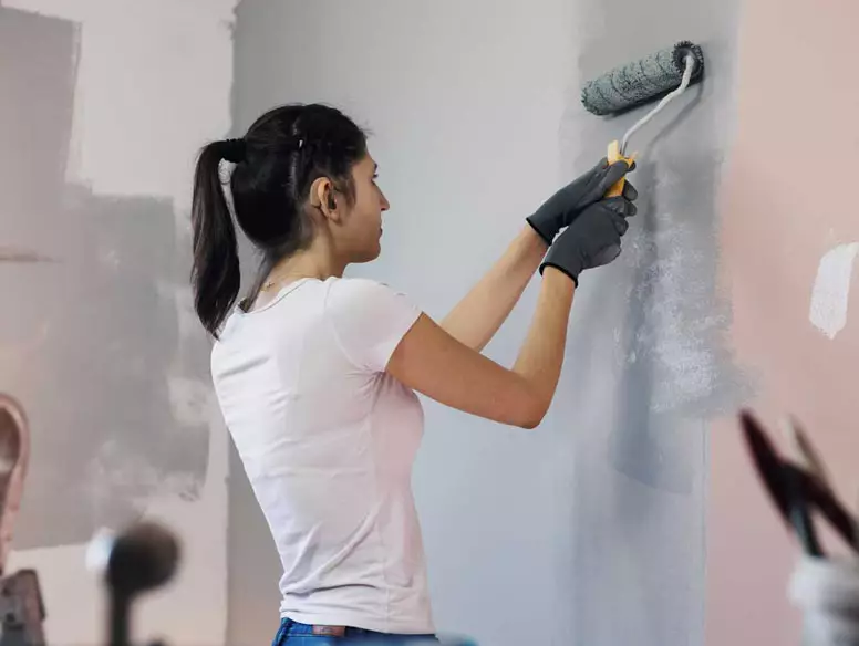 Woman painting interior wall with roller