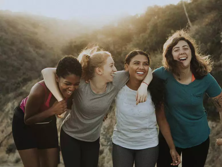 Group of 4 women laughing while hiking