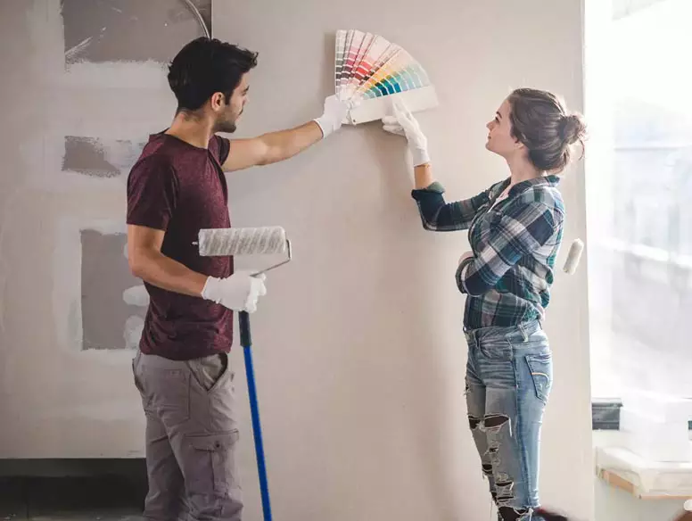 Couple looking at paint swatches next to wall