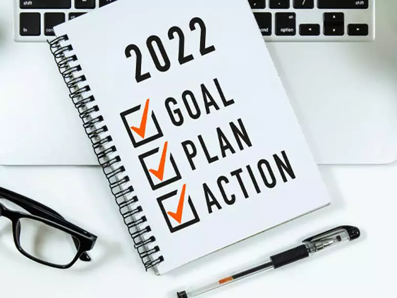 Laptop, glasses, pen and a notepad with 2022 goals